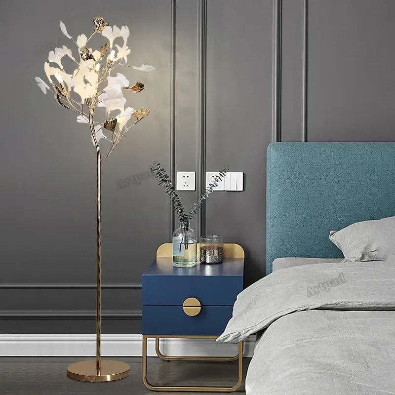 A tall slender decorbites ginkgo leaf floor lamp with gold metal frame and white gold leaf-shaped led lights for reading