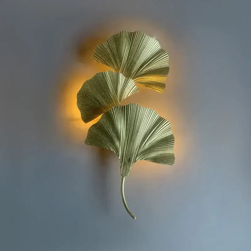 Gold-toned metallic wall lamp shaped like three overlapping ginkgo leaves with slender stem by decorbites ginkgo leaf