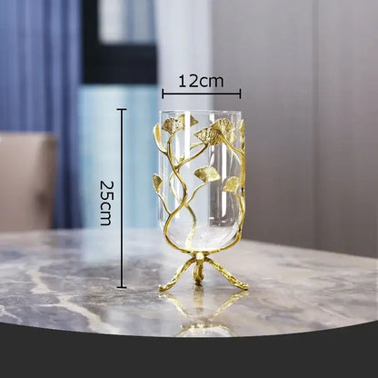 A clear glass vase with a golden ginkgo leaf metal frame and ornate legs from decorbites ginkgo leaf collection