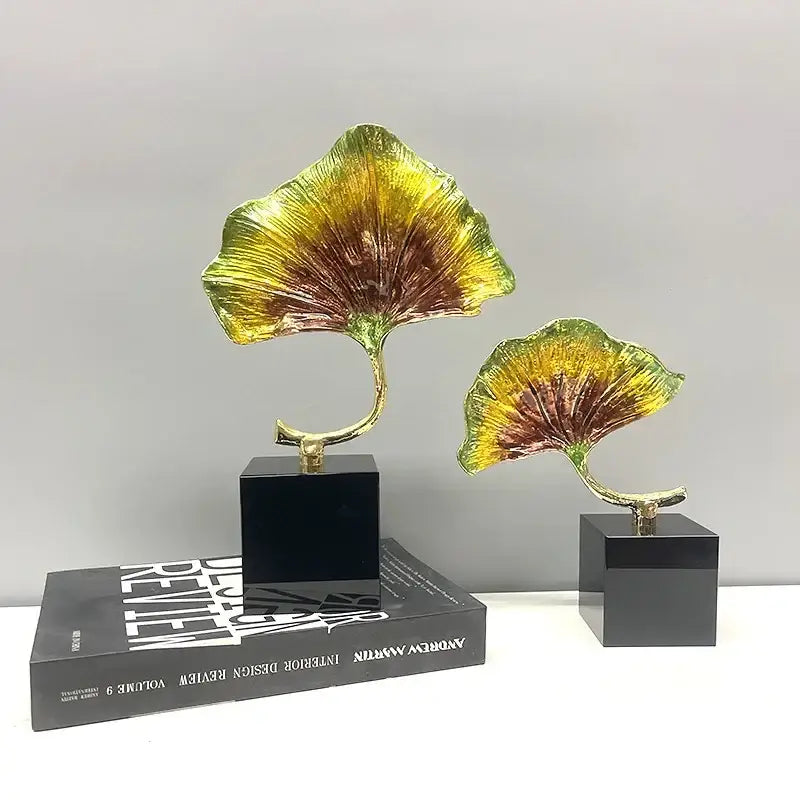 Two metallic ginkgo leaf metal sculptures with golden yellow and brown gradient finish on black bases decorbites ginkgo leaf