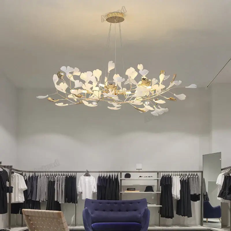 A decorbites ginkgo leaves chandelier with white and gold leaf accents suspended from a brass circular fixture