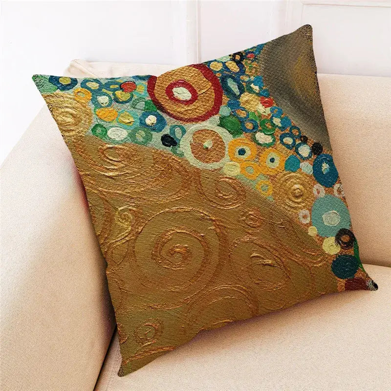 Square linen cushion cover with embroidered swirling gold ginkgo leaves and vibrant teal red yellow motifs by DecorBites