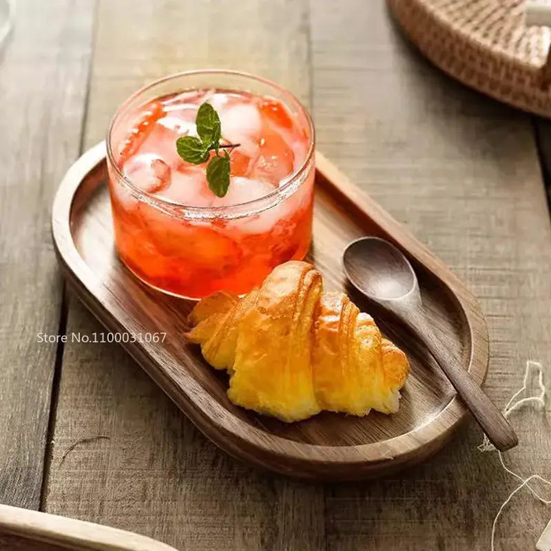 A clear decorbites glass afternoon tea dessert bowl filled with vibrant orange iced drink and fresh mint on wooden tray