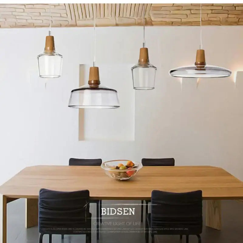 Decorbites glass and wood pendant light with clear glass and wooden accents hanging above a dining table