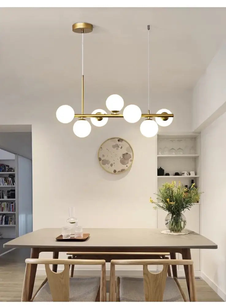 DecorBites™ gold-toned glass ball chandelier with multiple spherical bulbs in a linear design for dining room lighting
