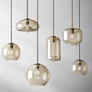 Set of modern decorbites™ glass pendant lights with smoked glass, brass accents, and exposed filament bulbs