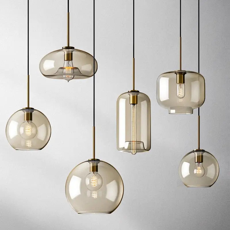 Set of modern decorbites™ glass pendant lights with smoked glass, brass accents, and exposed filament bulbs