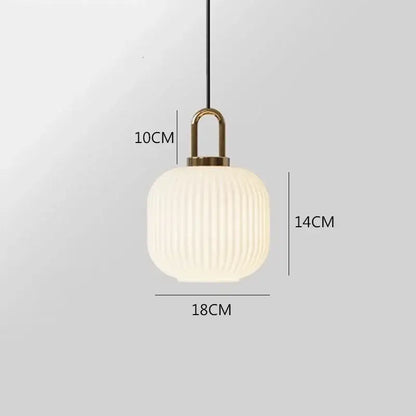 A modern pendant light with a frosted white glass stripe shade and brass fixture by Decorbites for dining rooms
