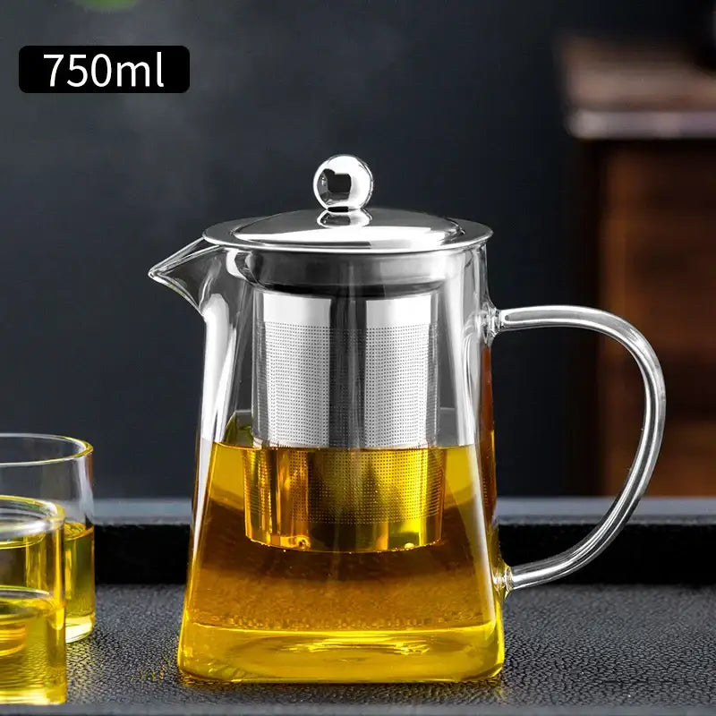Clear glass tea pot with stainless steel lid and built-in filter filled with golden tea by DecorBites glass tea