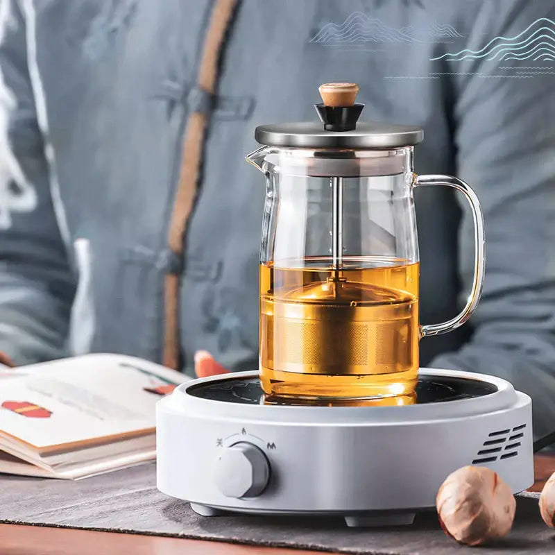 Decorbites glass tea pot with stainless steel lid and wooden knob filled with golden herbal tea