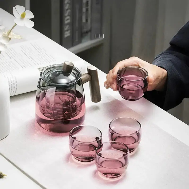 Transparent glass tea pot with wooden handle and lid plus four translucent pink glasses from DecorBites glass tea set