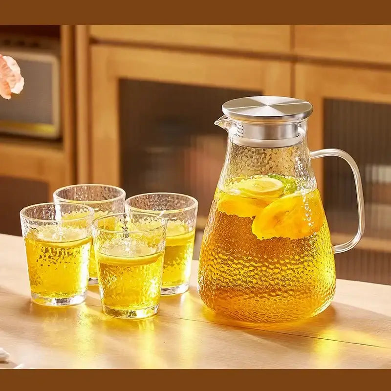 Clear textured glass pitcher with silver lid and handle filled with lemon tea from decorbites glass tea set