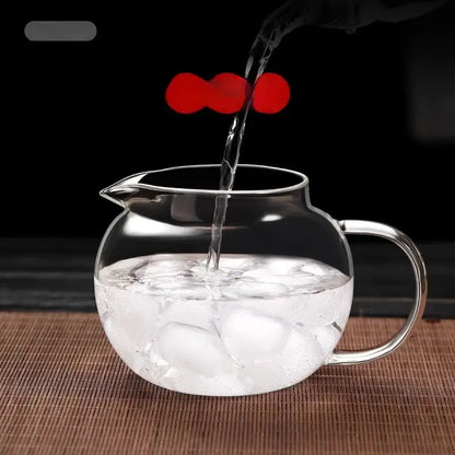 Clear glass decorbites glass teapot with curved handle filled with ice cubes and water being poured in for kung fu style tea