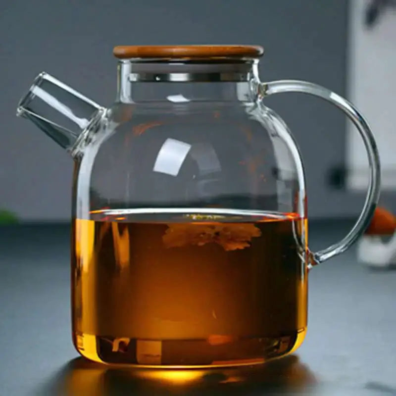 Clear glass teapot cold water jug with wooden lid and handle filled with amber tea by decorbites glass teapot
