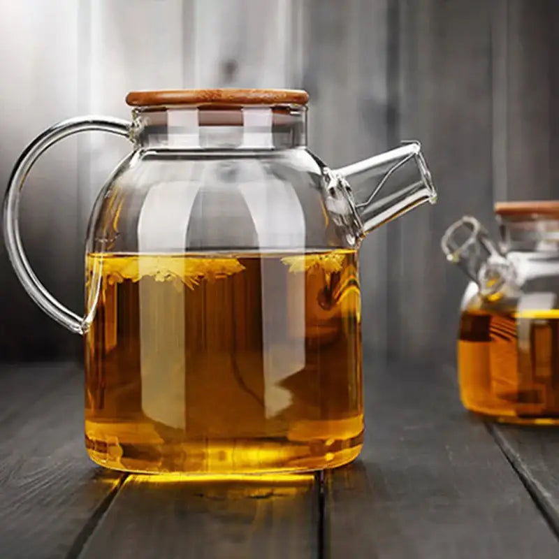Clear glass teapot cold water jug with wooden lid and handle filled with golden tea by decorbites glass teapot