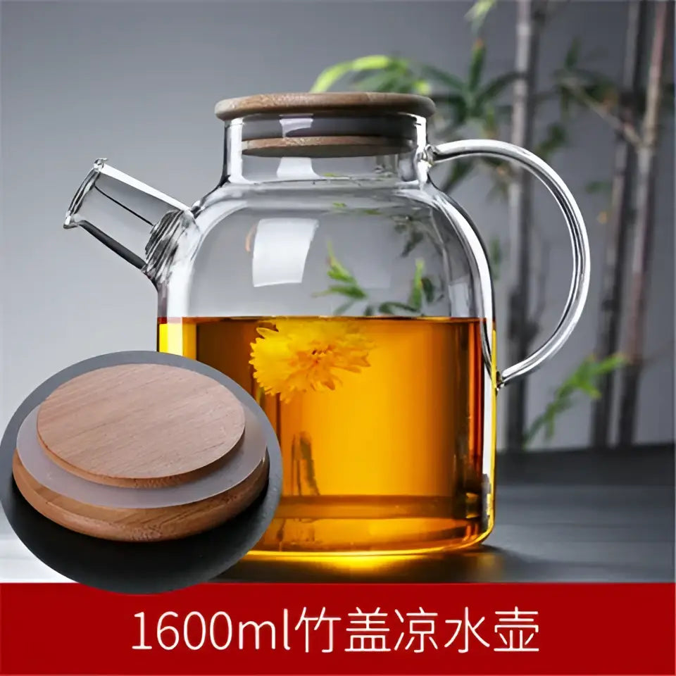 Clear glass teapot cold with wooden lid and handle filled with golden tea and floating yellow flower decorbites glass teapot