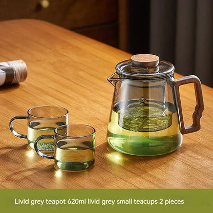 Clear glass decorbites glass teapot with wooden lid and handle, paired with two matching clear glass teacups