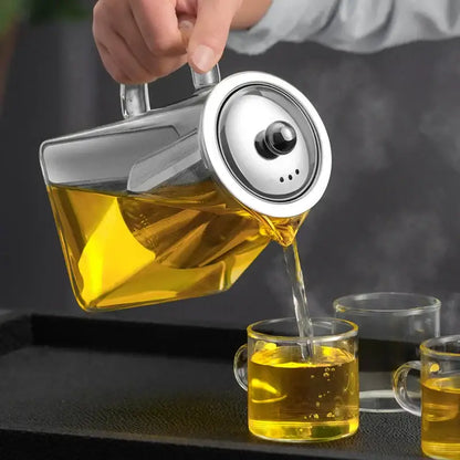 A sleek decorbites glass teapot with stainless steel lid pours golden tea into clear cups in a kungfu tea set