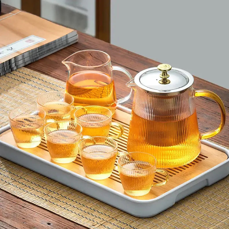 Clear glass teapot puer with silver lid gold knob and matching textured glass cups on bamboo tray decorbites glass teapot set