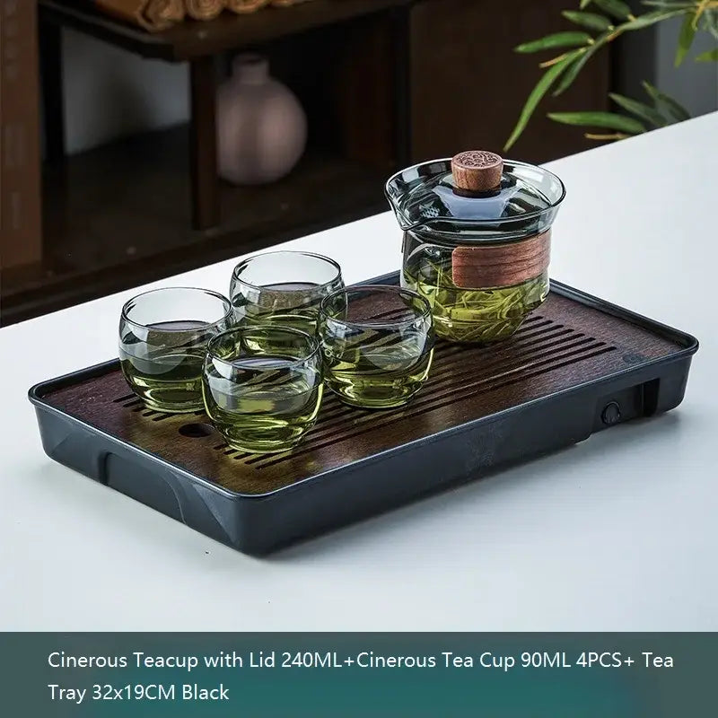 Black ceramic tea tray with decorbites glass teapot set and four glass cups featuring bamboo accents for kung fu tea