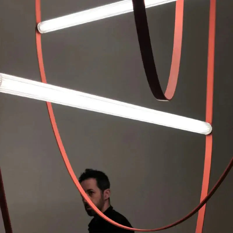 A modern decorbites glass tube pendant light with white fluorescent tubes and curved orange ribbons for living room