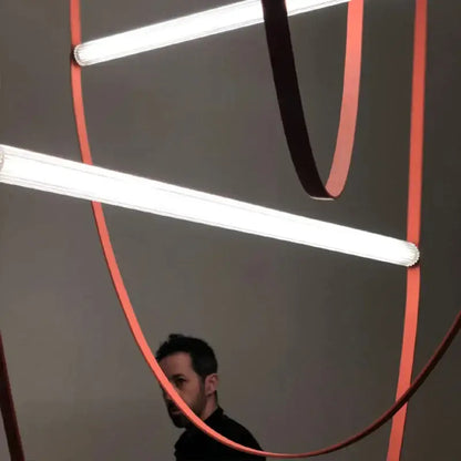 A modern decorbites glass tube pendant light with white fluorescent tubes and curved orange ribbons for living room