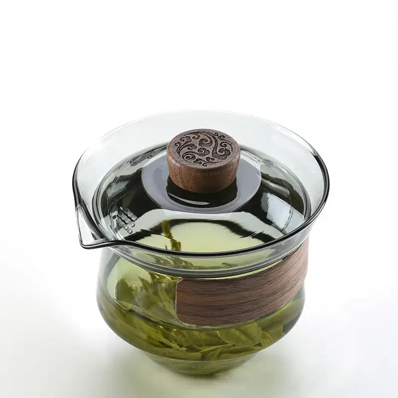 Clear glass decorbites glass tureen teapot with wooden lid and band containing green tea leaves for kung fu tea set