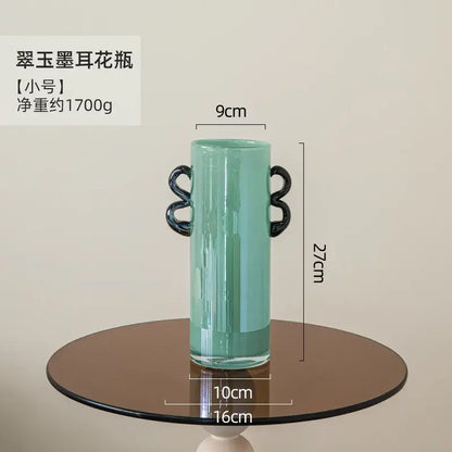 A sleek mint-green decorbites glass vase with black loop handles for flower arrangement and home decoration