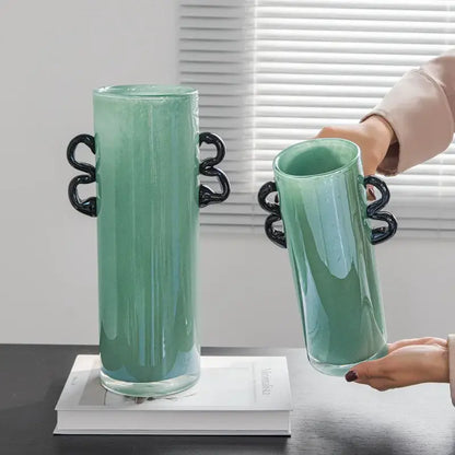A translucent mint-green decorbites glass vase with sleek black twisted handles for flower arrangement and home decoration