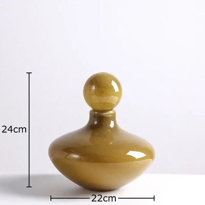 A glossy amber glass vase decanter with a rounded body and spherical stopper for decorbites glass vase flower arrangement