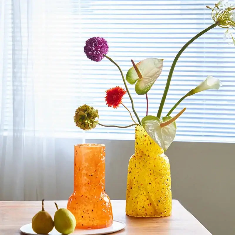 Vibrant orange and yellow speckled decorbites glass vase holding colorful flowers for hydroponic terrarium use