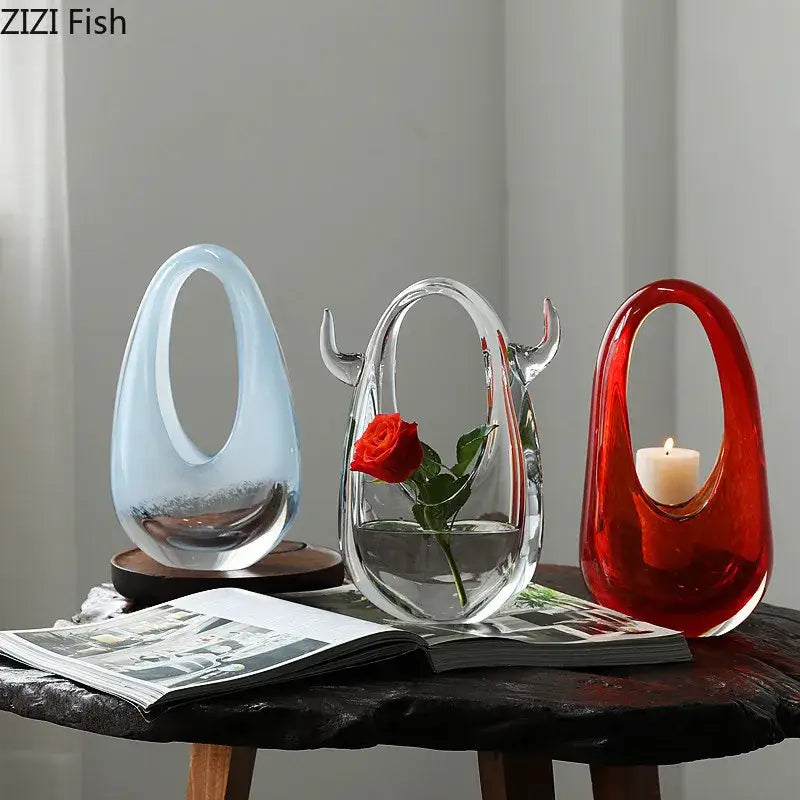 Three decorbites glass vases with organic shapes in light blue, clear with rose, and red holding a candle for elegant decoration