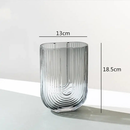 A sleek transparent decorbites glass vase with vertical ribbed texture and modern curved design for flower arrangement