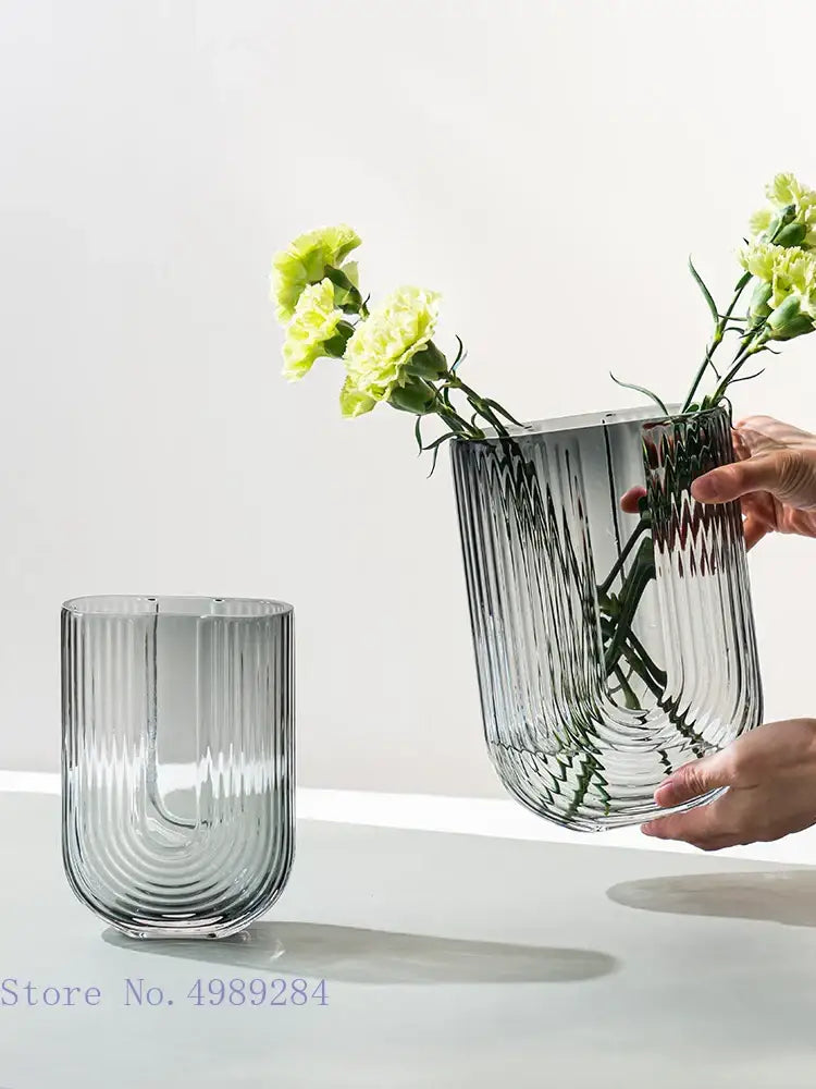 A sleek transparent decorbites glass vase with vertical ribbed detailing and modern curved design for flower arrangement