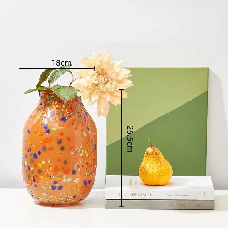 A vibrant orange decorbites glass vase with colorful speckles holding a single cream flower for home decor and hydroponic plants