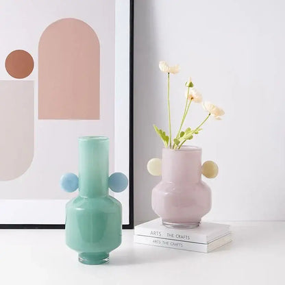 Pastel pink decorbites glass vase with rounded bulbous sides and two light yellow spherical handles for floral arrangement
