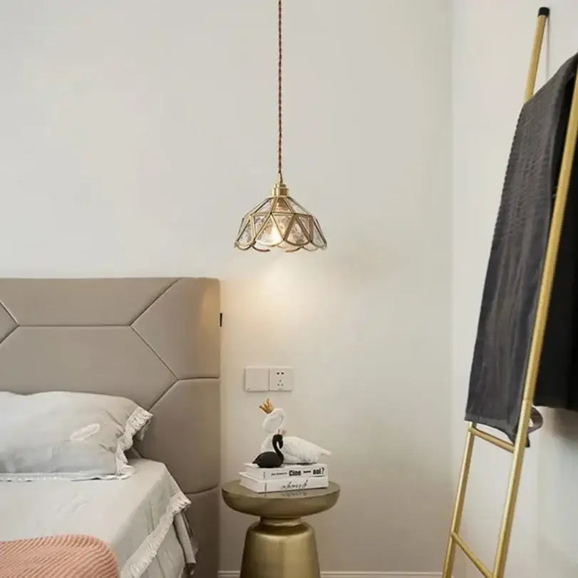 A brass DecorBites glass vintage pendant light with a geometric faceted glass shade hanging from a braided cord