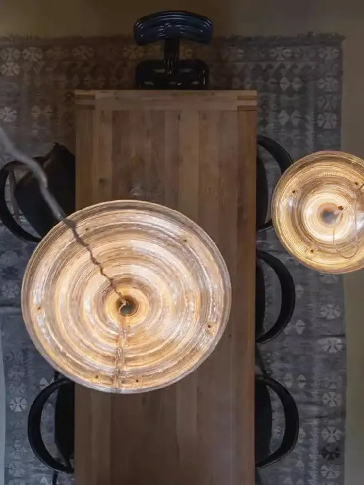 Two amber glass pendant lights with concentric rings hang above a wooden table decorbites glass wall lamp modern dimmable