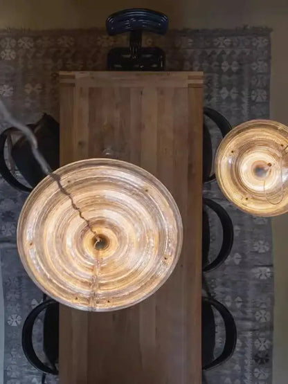 Two amber glass pendant lights with concentric rings hang above a wooden table decorbites glass wall lamp modern dimmable