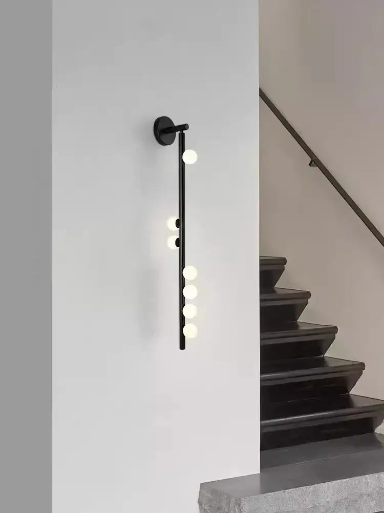 Black decorbites glass wall lamp with five glowing spherical bulbs on minimalist rod for modern living spaces