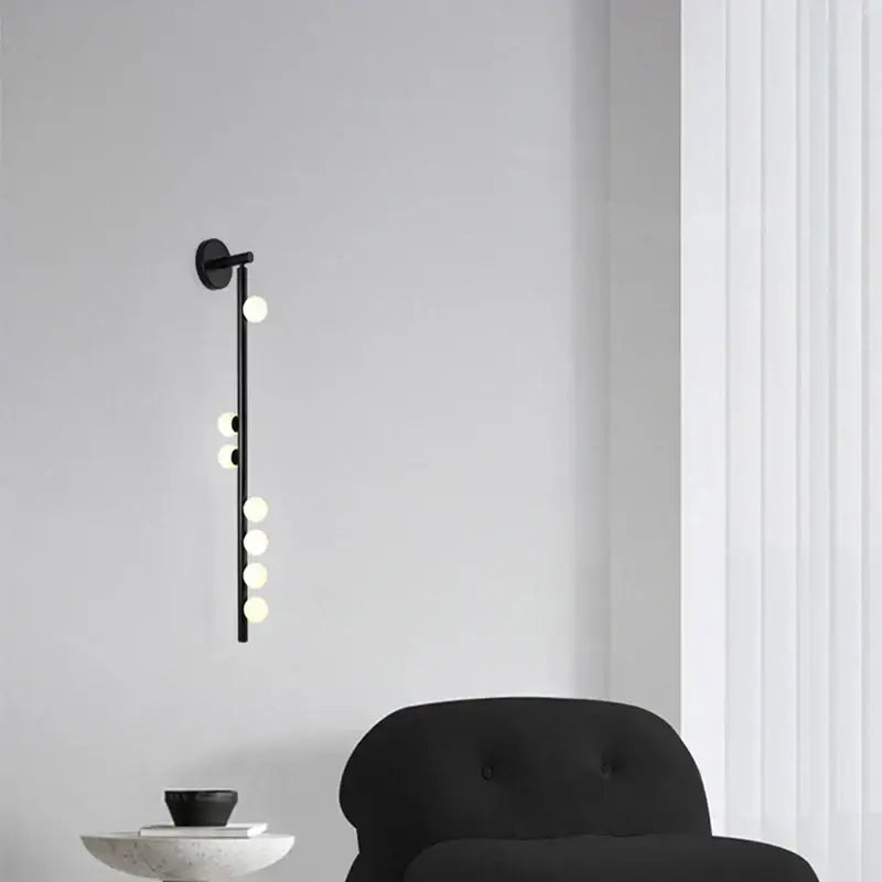 Black DecorBites glass wall lamp with slender rod and five glowing spherical bulbs for hotel villa living room