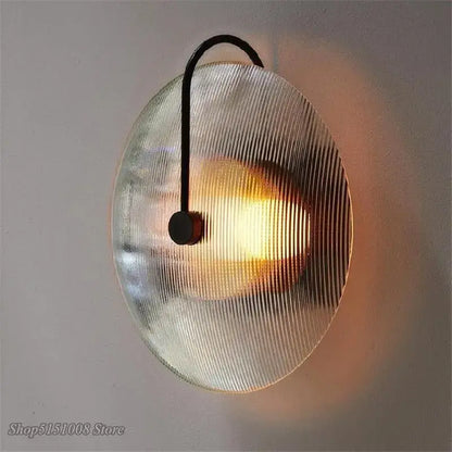 A black metal decorbites glass wall lamp with a circular ribbed glass shade for minimalist home decor lighting