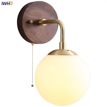 Brass-finished DecorBites glass wall light fixture with round walnut wood backplate and frosted glass globe