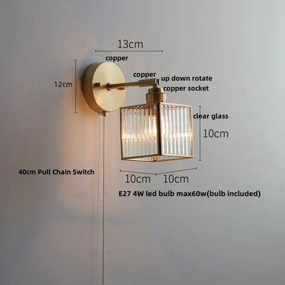 A brass-finished copper decorbites glass wall light sconce with clear glass cube and vertical ribbed panels for modern lighting