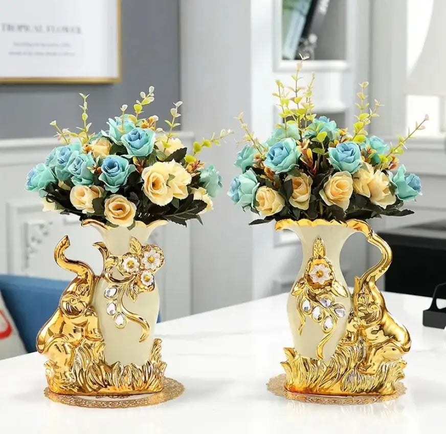Elegant cream ceramic vases with gold-gilded elephant figurines and blue yellow roses in DecorBites™ gold glass vase for decor