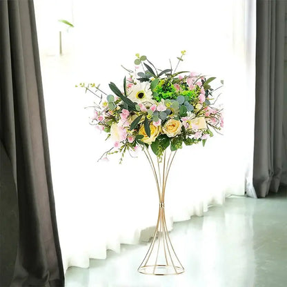 A gold-toned iron flower vase by DecorBites holds artificial pink, yellow, and white flowers with green foliage