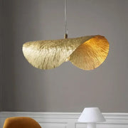 A sculptural gold lotus leaf pendant light with a textured leaf design hangs from the ceiling by decorbites