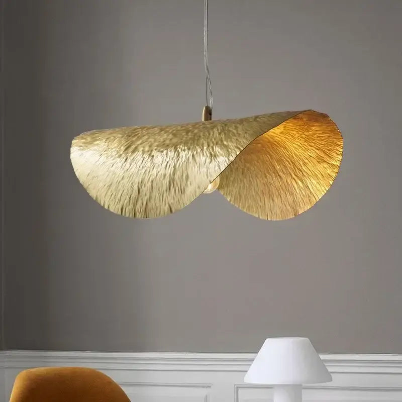 A sculptural gold lotus leaf pendant light with a textured leaf design hangs from the ceiling by decorbites