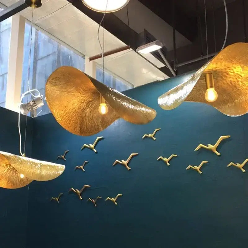 Gold lotus leaf pendant light by decorbites featuring textured gold lotus leaf design with warm glowing bulbs hanging from ceiling