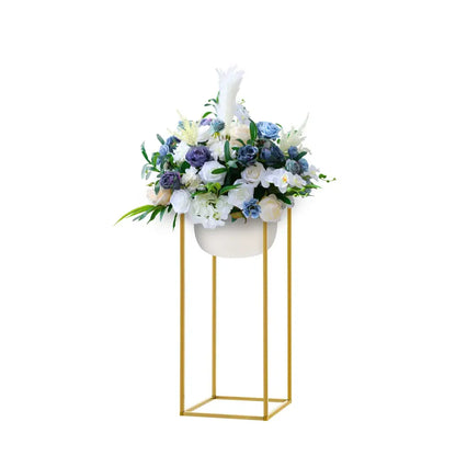 Elegant white ceramic planter with gold metal stand filled with blue and white flowers for wedding flower stand use